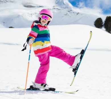 Bambina che gioca con gli sci sulla neve