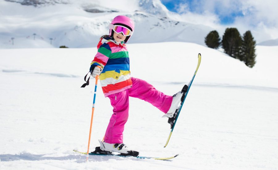 Bambina che gioca con gli sci sulla neve